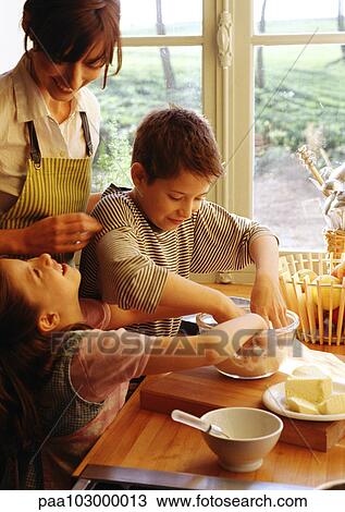 Two children and mother cooking in kitchen, children with hands in bowl, mother in apron smiling View Large Photo Image Stock Image - Two children and mother cooking in kitchen, children with hands in bowl, mother in apron smiling. Fotosearch