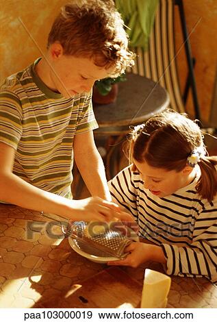 Stock Photo - Two children grating cheese . Fotosearch