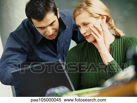 Stock Photography - Businessman and woman looking at laptop computer. Fotosearch