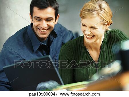 Stock Photo - Businessman and woman with laptop computer, smiling. Fotosearch