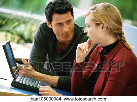 Picture - Man and woman talking and using laptop computer. Fotosearch