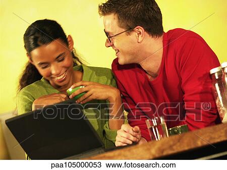 Stock Image - Man and woman with laptop computer, smiling. Fotosearch