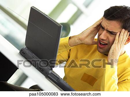 Man holding his head, looking at laptop computer View Large Photo Image Stock Image - Man holding his head, looking at laptop computer. Fotosearch