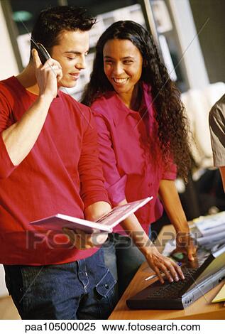 Man with cell phone, woman using laptop computer View Large Photo Image Stock Photography - Man with cell phone, woman using laptop computer. Fotosearch