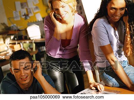 Stock Photo - Three people using cell phones in office. Fotosearch