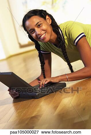 Woman lying on floor with laptop computer, portrait View Large Photo Image Stock Photo - Woman lying on floor with laptop computer, portrait. Fotosearch