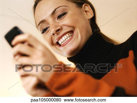 Woman smiling with cell phone in hands, low angle view View Large Photo Image Stock Image - Woman smiling with cell phone in hands, low angle view. Fotosearch