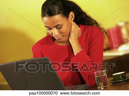 Woman working on laptop with hand on neck View Large Photo Image Stock Image - Woman working on laptop with hand on neck. Fotosearch