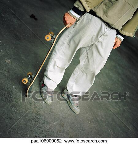 Person holding skateboard, low section View Large Photo Image Stock Image - Person holding skateboard, low section. Fotosearch