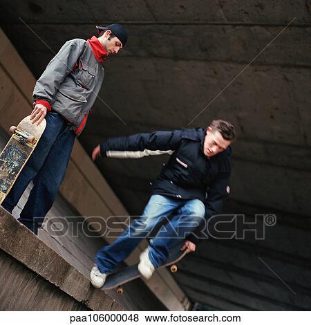 Two teenagers with skateboards, one jumping down from a wall View Large Photo Image Stock Photo - Two teenagers with skateboards, one jumping down from a wall. Fotosearch