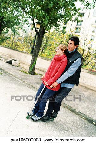Stock Image - Two young people standing on push scooter. Fotosearch