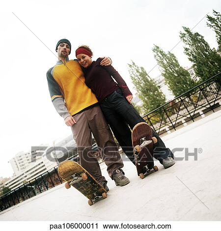 Young man and woman standing together with skateboards, portrait View Large Photo Image Stock Image - Young man and woman standing together with skateboards, portrait. Fotosearch