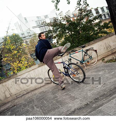 Young man getting on bike View Large Photo Image Picture - Young man getting on bike. Fotosearch