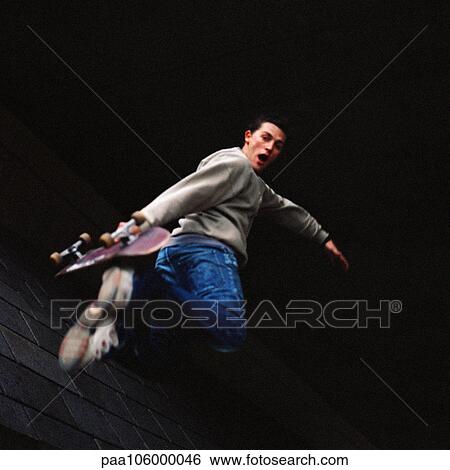 Young man in mid-air holding skateboard View Large Photo Image Stock Photograph - Young man in mid-air holding skateboard. Fotosearch