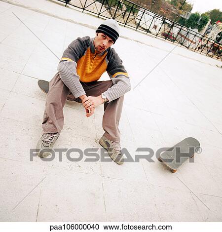 Young man sitting on skateboard View Large Photo Image Stock Image - Young man sitting on skateboard. Fotosearch
