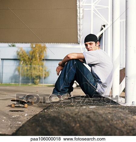 Young man with skateboard sitting outdoors, side view, portrait View Large Photo Image Stock Photo - Young man with skateboard sitting outdoors, side view, portrait. Fotosearch