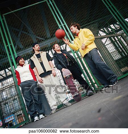 Young people standing against fence, one spinning basketball View Large Photo Image Stock Image - Young people standing against fence, one spinning basketball. Fotosearch