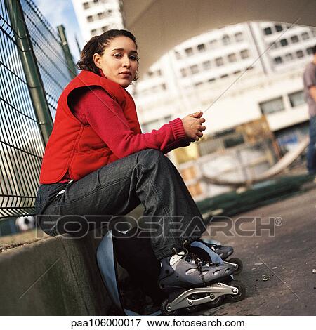 Stock Photo - Young woman wearing inline skates, portrait. Fotosearch