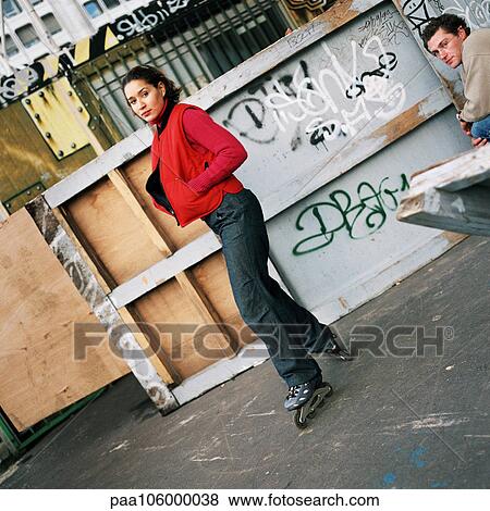 Young woman wearing inline skates, young man sitting, portrait View Large Photo Image Stock Photo - Young woman wearing inline skates, young man sitting, portrait. Fotosearch
