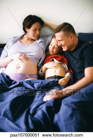 Couple and child in bed together, pregnant woman and child showing stomachs View Large Photo Image Stock Image - Couple and child in bed together, pregnant woman and child showing stomachs. Fotosearch