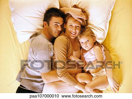 Couple and child lying on bed, elevated view, portrait View Large Photo Image Stock Image - Couple and child lying on bed, elevated view, portrait. Fotosearch
