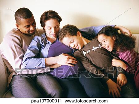 Couple and children sitting on sofa View Large Photo Image Stock Image - Couple and children sitting on sofa. Fotosearch
