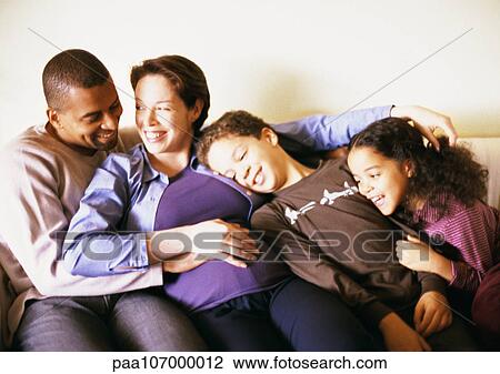 Stock Image - Couple and children sitting on sofa. Fotosearch