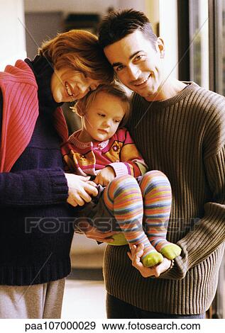 Stock Photo - Couple holding child, smiling, portrait. Fotosearch