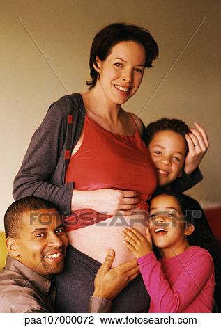 Stock Image - Man and children around pregnant woman's exposed stomach. Fotosearch