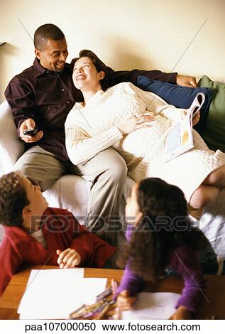Man and pregnant woman on sofa, children looking over shoulders at them View Large Photo Image Stock Image - Man and pregnant woman on sofa, children looking over shoulders at them. Fotosearch