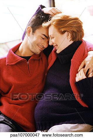 Man and pregnant woman sitting with arms around each other View Large Photo Image Stock Photo - Man and pregnant woman sitting with arms around each other. Fotosearch