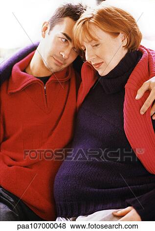 Man and pregnant woman sitting with arms around each other View Large Photo Image Stock Photo - Man and pregnant woman sitting with arms around each other. Fotosearch