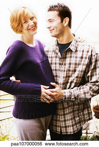 Man and pregnant woman standing with arms around each other View Large Photo Image Stock Photograph - Man and pregnant woman standing with arms around each other. Fotosearch