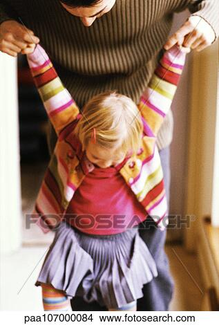 Picture - Man holding child's hands in air, both looking down. Fotosearch
