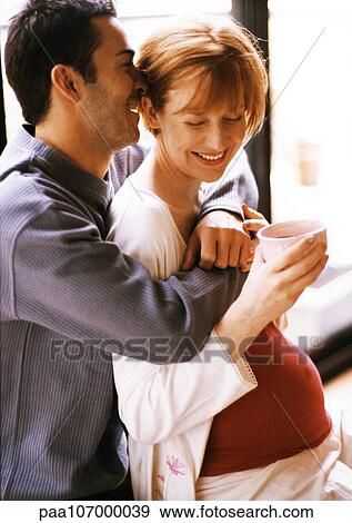 Man hugging pregnant woman from behind, smiling View Large Photo Image Stock Photo - Man hugging pregnant woman from behind, smiling. Fotosearch