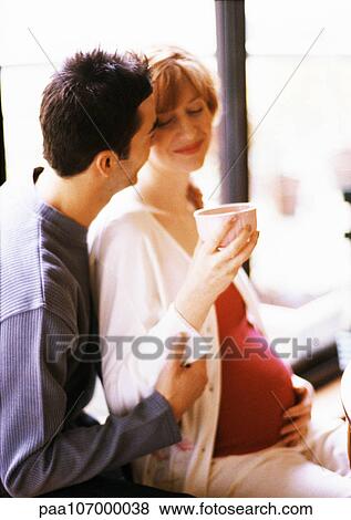 Man sitting behind pregnant woman with arms around her, side view View Large Photo Image Stock Photo - Man sitting behind pregnant woman with arms around her, side view. Fotosearch