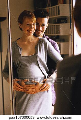 Man standing with arms around pregnant woman in front of mirror View Large Photo Image Stock Image - Man standing with arms around pregnant woman in front of mirror. Fotosearch