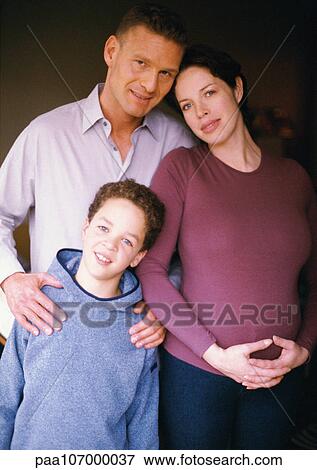 Stock Photo - Pregnant woman and man standing with child, smiling, portrait. Fotosearch