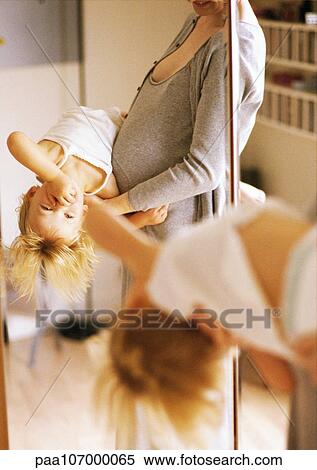 Pregnant woman holding child in front of mirror View Large Photo Image Stock Photography - Pregnant woman holding child in front of mirror. Fotosearch