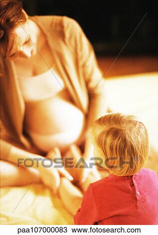 Pregnant woman sitting indian style, holding child's legs View Large Photo Image Stock Image - Pregnant woman sitting indian style, holding child's legs. Fotosearch