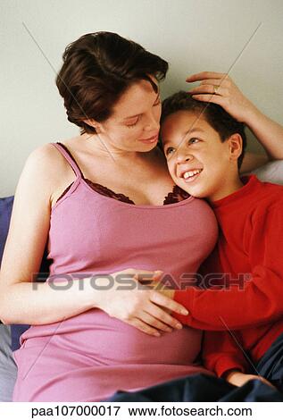 Pregnant woman sitting with arm around child View Large Photo Image Stock Photo - Pregnant woman sitting with arm around child. Fotosearch