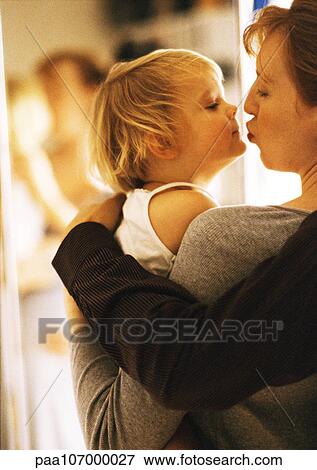 Woman holding and kissing child, side view, close-up View Large Photo Image Stock Photo - Woman holding and kissing child, side view, close-up. Fotosearch