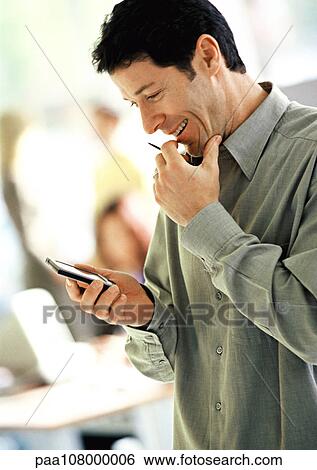 Businessman looking at electronic organizer, smiling View Large Photo Image Stock Photograph - Businessman looking at electronic organizer, smiling. Fotosearch