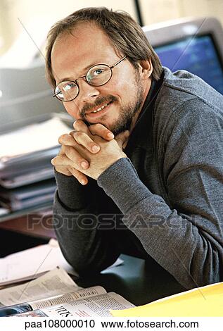 Businessman sitting at desk with hands clasped, portrait View Large Photo Image Stock Image - Businessman sitting at desk with hands clasped, portrait. Fotosearch