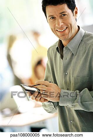 Businessman using pocket computer, smiling, portrait View Large Photo Image Stock Photography - Businessman using pocket computer, smiling, portrait. Fotosearch