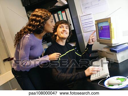 Stock Photo - Man and woman looking at computer. Fotosearch