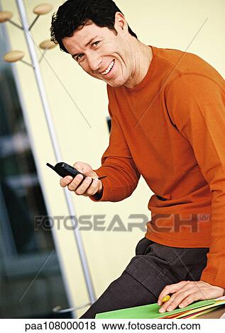 Stock Photo - Man holding cell phone, portrait. Fotosearch