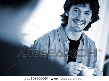 Man holding teacup, smiling, at second person in foreground, blurred View Large Photo Image Stock Image - Man holding teacup, smiling, at second person in foreground, blurred. Fotosearch