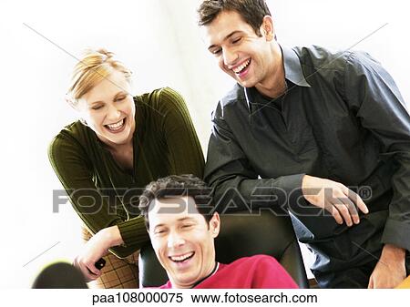 Man sitting in chair, second man and woman looking over his shoulder View Large Photo Image Stock Photography - Man sitting in chair, second man and woman looking over his shoulder. Fotosearch
