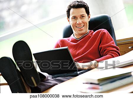 Man sitting with feet on desk and laptop on lap View Large Photo Image Stock Photo - Man sitting with feet on desk and laptop on lap. Fotosearch